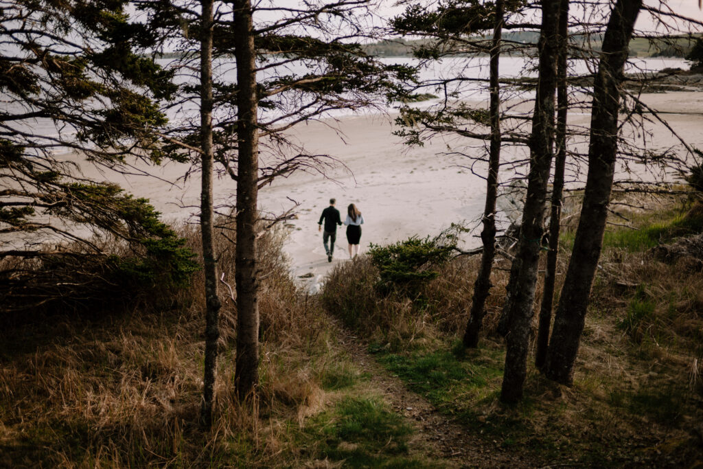 Couple walking through the trees onto Rissers Beach, Nova Scotia