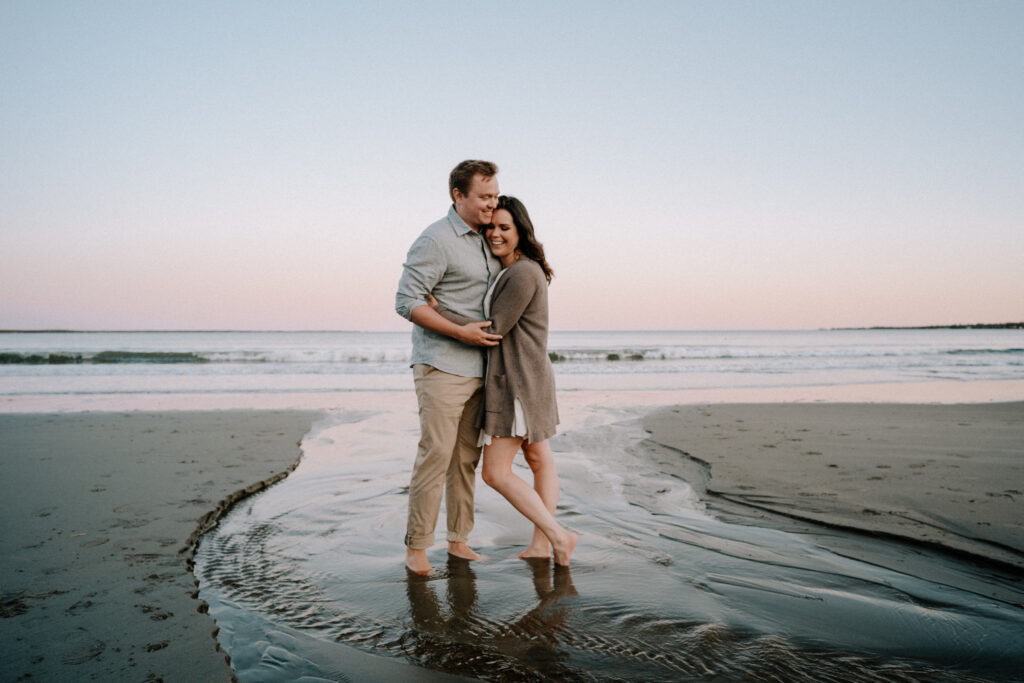 Newly engaged couple standing barefoot on Rissers Beach, Nova Scotia