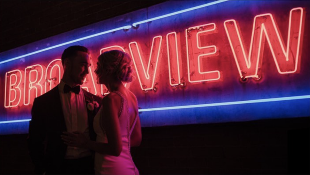 Couple standing in front of neon broadview sign at broadview hotel wedding in Toronto.