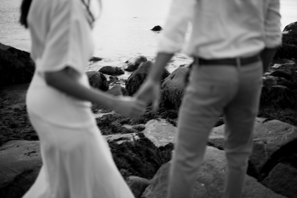 Wedding couple holding hands on the rocks near Bull Point Estate wedding venue.