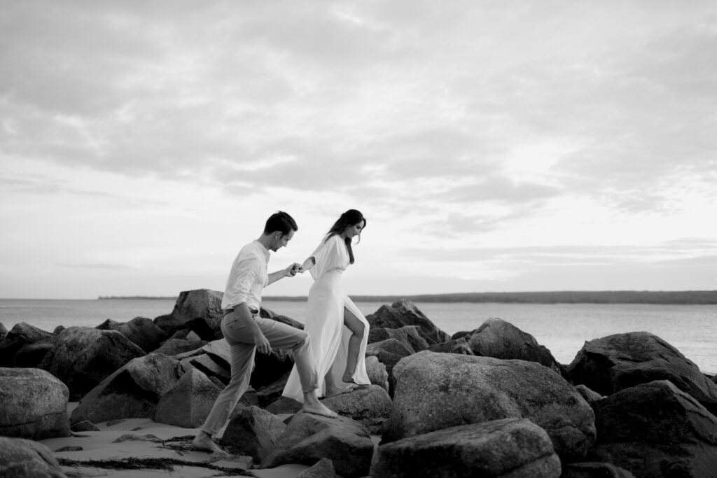 Couple holding hands while walking on the rocks in Port Mouton. Photographed by Nova Scotia Wedding Photographer.