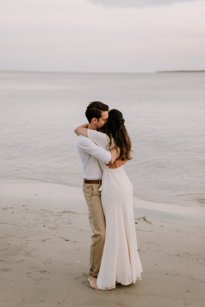 Candid moment of couple hugging on the beach near Bull Point Estates in Port Mouton, Nova Scotia.