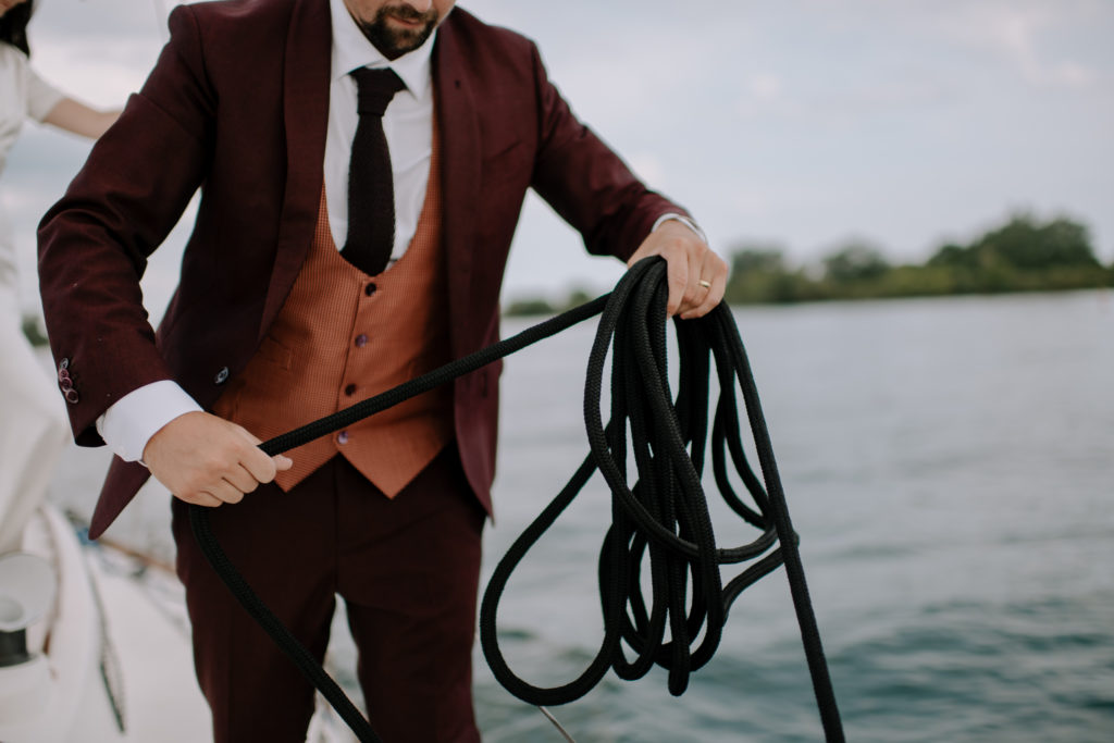 Groom holding rope on intimate sailboat elopement in Nova Scotia