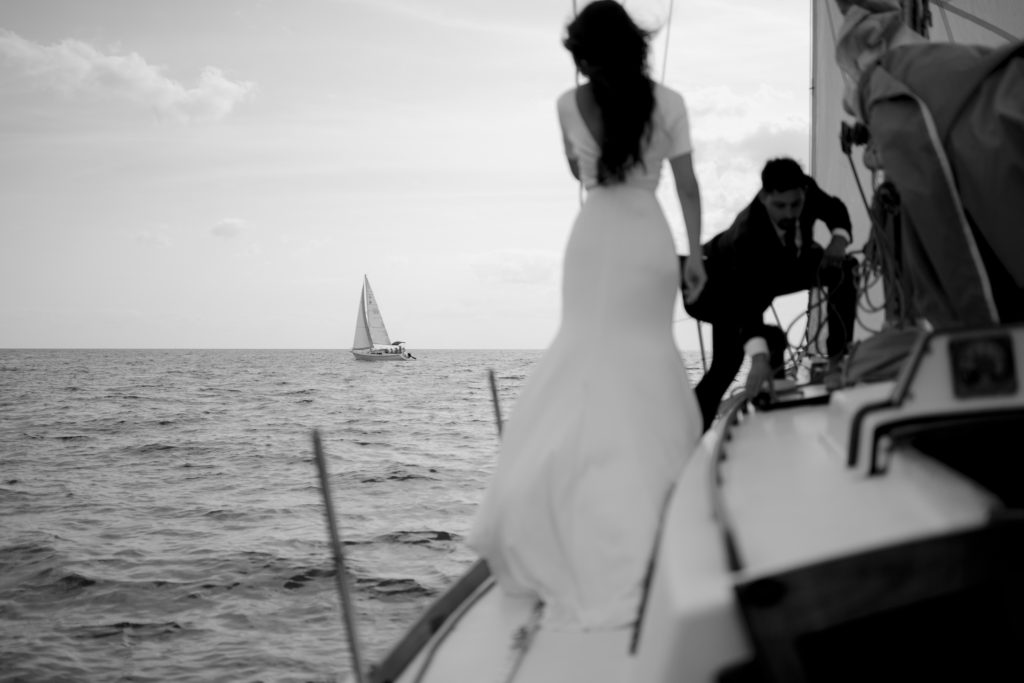 Wedding couple on a sailboat looking out to sea at another sailboat in Halifax