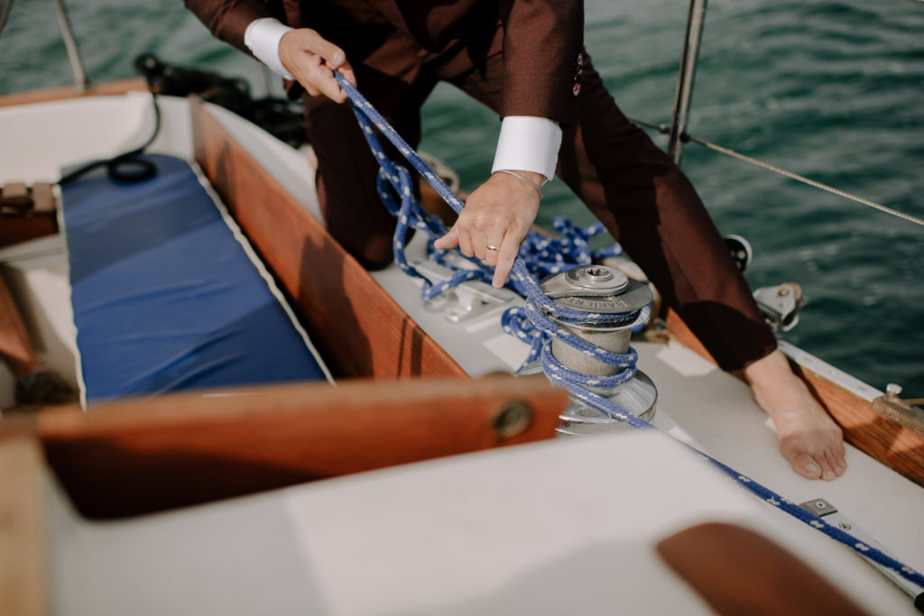 Groom tying rope off on sailboat after wedding in Halifax